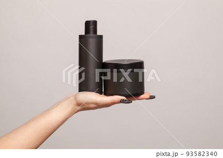 Empty black plastic bottles in female hand on white background 93582340