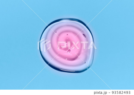 Light blue and pink round gradient transparent gel drop isolated on blue background. Top view. Virus protection or cosmetics concept. Face Serum texture close up. Light blue and pink round gradient transparent gel drop isolated on blue background. Top view. Virus protection or cosmetics concept. Face Serum texture close up. 93582493