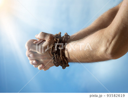 Chained hands praying for help 93582619