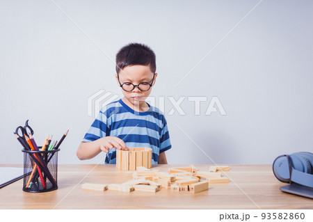 Asian boy playing with a wooden puzzle Asian boy playing with a wooden puzzle 93582860