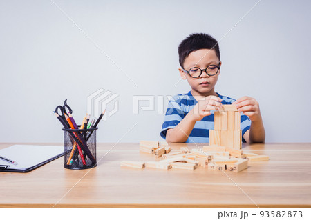 Asian boy playing with a wooden puzzle 93582873