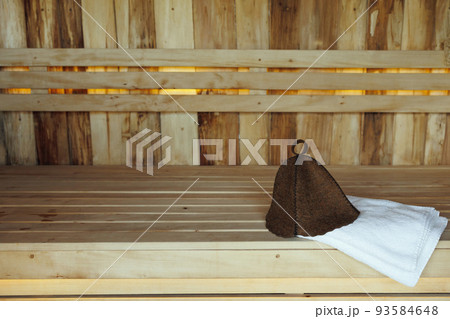 Bath hat and white towel on wooden boards in the sauna 93584648