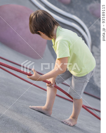Boy climbes up a concrete slope of modern children's sports and playground. Kid overcomes fear and learn new things. Active leisure outdoors. Sporty lifestyle. Boy climbes up a concrete slope of modern children's sports and playground. Kid overcomes fear and learn new things. Active leisure outdoors. Sporty lifestyle. 93589115