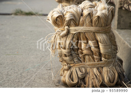 A thick brown  bundle of  raw jute has on the ground     93589990