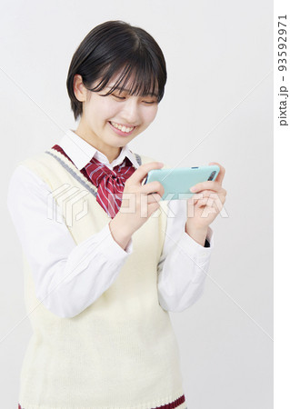 白背景で笑顔でスマホを見る女子高生 93592971