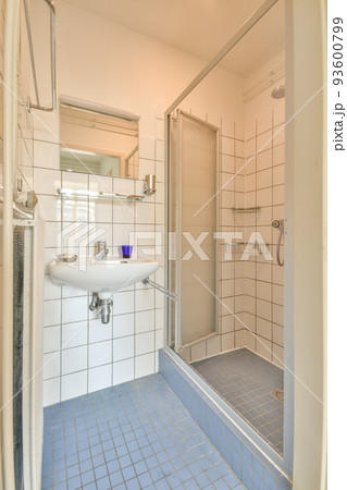 Sinks with mirrors and shower box with glass door in modern bathroom with white tiled walls 93600799