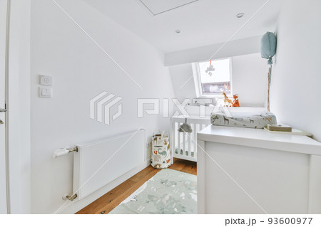 Interior of white room with baby crib and armchair near window in daylight 93600977