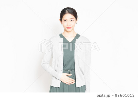 白背景の前に立って、お腹に手を当てる女性 白背景の前に立って、お腹に手を当てる女性 93601015