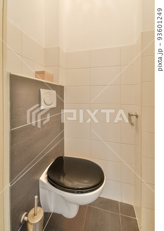 Wall hung toilet and small sink in corner in lavatory room with beige tile and shower Wall hung toilet and small sink in corner in lavatory room with beige tile and shower 93601249