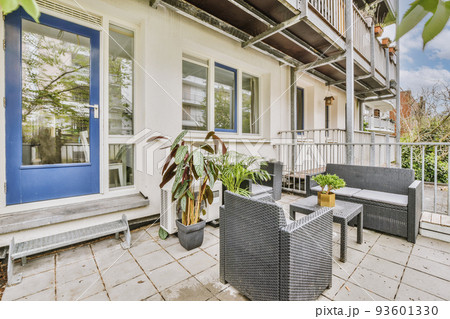 Neat paved patio with sitting area and small garden near wooden fence 93601330