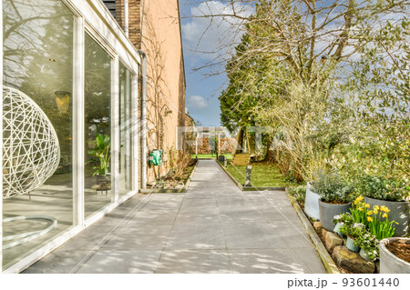 Neat paved patio with sitting area and small garden near wooden fence 93601440