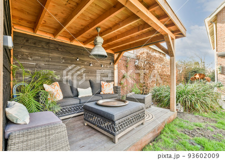 Neat paved patio with sitting area and small garden near wooden fence 93602009
