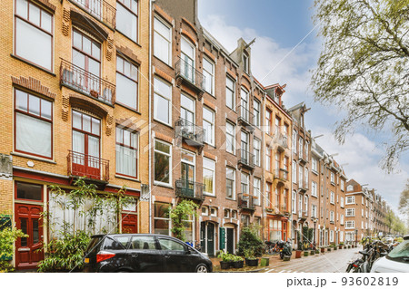 Panorama view of brick houses from an empty sidewalk street with cars, trees and lanterns Panorama view of brick houses from an empty sidewalk street with cars, trees and lanterns 93602819