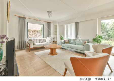 Shabby wooden table with chairs and vase located near comfortable couch against light walls with decorations and TV in modern apartment Shabby wooden table with chairs and vase located near comfortable couch against light walls with decorations and TV in modern apartment 93603137