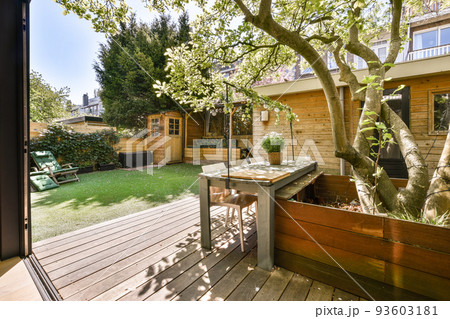 Neat paved patio with sitting area and small garden near wooden fence Neat paved patio with sitting area and small garden near wooden fence 93603181
