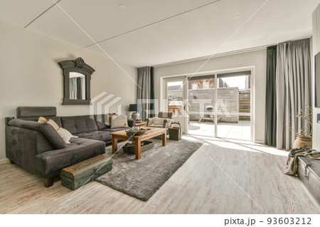 Cozy interior design of living room furnished with comfortable couch and wooden table decorated with carpet and lamp in modern attic apartment with white walls and column 93603212