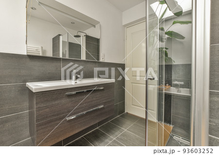 Sinks with mirrors and shower box with glass door in modern bathroom with white tiled walls 93603252