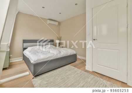 Home interior design of bedroom with bed and wooden wardrobe placed in corner near window in modern apartment 93603253