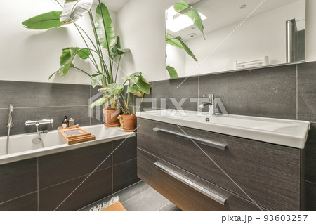 Sinks with mirrors and clean bathtub located with glass door in modern bathroom with white tiled walls Sinks with mirrors and clean bathtub located with glass door in modern bathroom with white tiled walls 93603257