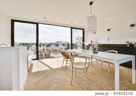 Home interior design of modern loft apartment with open kitchen in minimalist style and spacious dining zone with table and chairs Home interior design of modern loft apartment with open kitchen in minimalist style and spacious dining zone with table and chairs 93603258