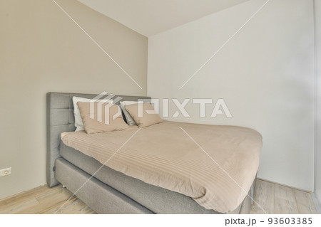 Comfortable bed covered with checkered blanket and located in light bedroom of modern apartment Comfortable bed covered with checkered blanket and located in light bedroom of modern apartment 93603385