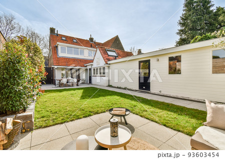 Neat paved patio with sitting area and small garden near wooden fence Neat paved patio with sitting area and small garden near wooden fence 93603454