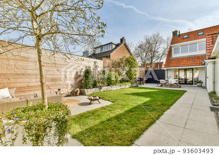 Neat paved patio with sitting area and small garden near wooden fence Neat paved patio with sitting area and small garden near wooden fence 93603493