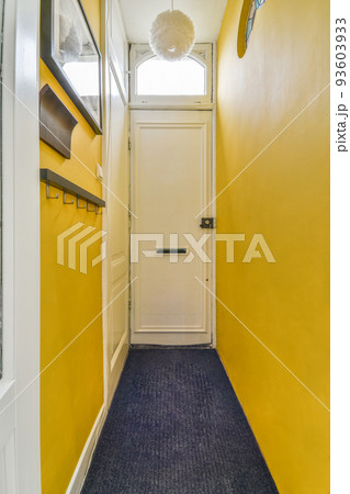 Light narrow hallway with many doors in yellow walls and glowing lamp over lumber floor Light narrow hallway with many doors in yellow walls and glowing lamp over lumber floor 93603933