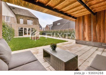 Neat paved patio with sitting area and small garden near wooden fence 93604268