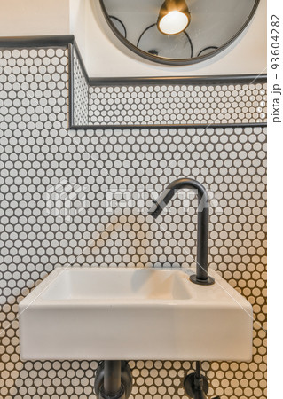 Sink with tap and liquid soap hanging on tiled wall under mirror in contemporary restroom at home Sink with tap and liquid soap hanging on tiled wall under mirror in contemporary restroom at home 93604282