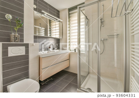 Flush toilet located between sink and shower in small tiled bathroom of contemporary apartment Flush toilet located between sink and shower in small tiled bathroom of contemporary apartment 93604331