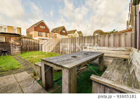Neat paved patio with sitting area and small garden near wooden fence 93605181