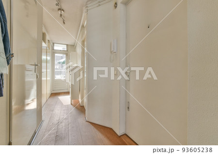 Light narrow hallway with many doors in white walls and glowing lamp over lumber floor Light narrow hallway with many doors in white walls and glowing lamp over lumber floor 93605238