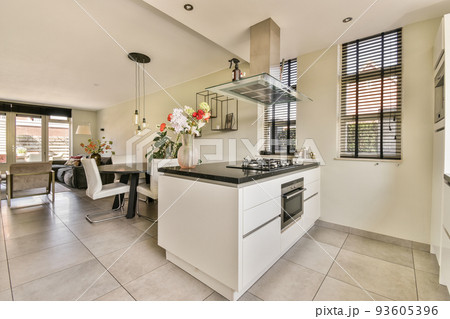 Spacious minimalist style dining room with table and chairs in modern apartment with white walls and wooden floor Spacious minimalist style dining room with table and chairs in modern apartment with white walls and wooden floor 93605396