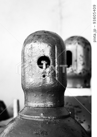 Compressed gas cylinders being stored vertically secured by a metal chain and a metal cap. 93605409