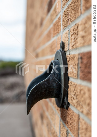 Brass metal down spout termination on the side of a brick building Brass metal down spout termination on the side of a brick building 93605583