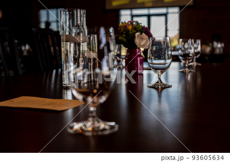 Formal dinner setting placement with an empty glass and light reflecting off the table. 93605634