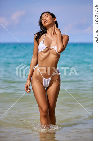 Beautiful asian girl in white bikini posing at the tropical beach 93607756
