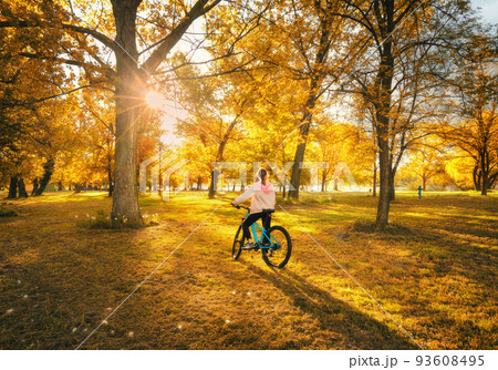 Woman riding a mountain bike and orange trees at sunset in autumn 93608495