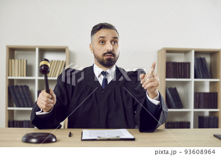Portrait of stern judge knocking on judge's gavel passes sentence and declares case closed. 93608964