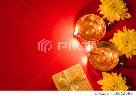 Happy Diwali. Diya oil lamp, flowers and gift boxes on red background. Celebrating the Indian traditional festival of light. 93612069