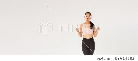 Full length of amazed and impressed female athlete in activewear, showing thumbs-up in approval and looking wondered, praise great workout program, fitness training app or gym membership prices 93614983