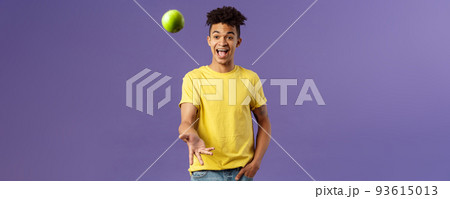 Holidays, vitamins and vacation concept. Portrait of handsome upbeat young male student asking friend something eat, catching apple and smiling happy, standing purple background 93615013