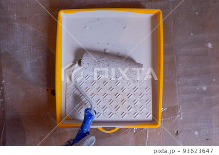 the builder dips the roller into the construction bath with paint the builder dips the roller into the construction bath with paint 93623647