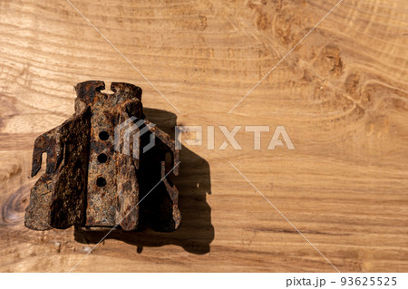 Splinter of a mine of the period WWII on wooden background. Rusty mortar mine from the Second World War. Copy space. Splinter of a mine of the period WWII on wooden background. Rusty mortar mine from the Second World War. Copy space. 93625525