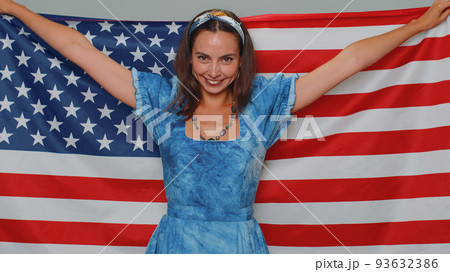 Lovely young woman waving and wrapping in American USA flag, celebrating, human rights and freedoms Lovely young woman waving and wrapping in American USA flag, celebrating, human rights and freedoms 93632386