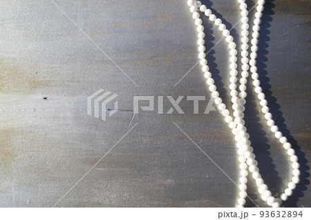 Pearl beads on a gray wooden background close-up. Pearl beads on a gray wooden background close-up. 93632894