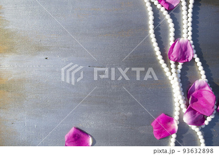 Pearl beads and rose petals on a gray wooden background close-up. Pearl beads and rose petals on a gray wooden background close-up. 93632898