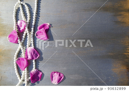 Pearl beads and rose petals on a gray wooden background close-up. Pearl beads and rose petals on a gray wooden background close-up. 93632899