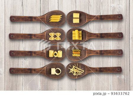 Wooden cooking spoons filled with various types dry pasta 93633762